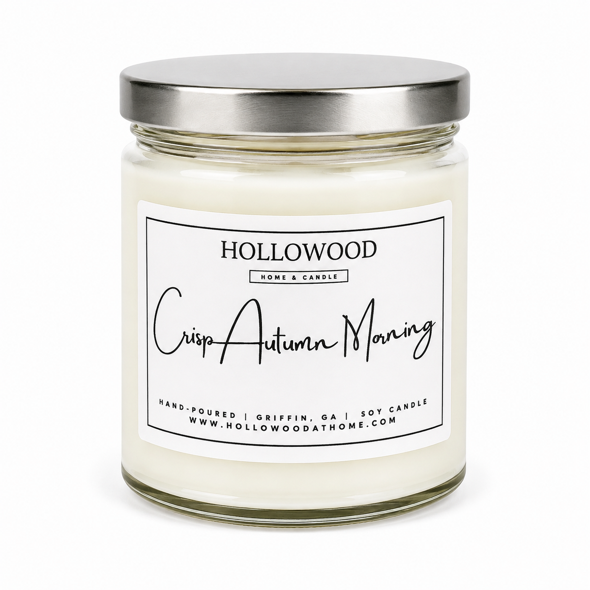 A glass jar candle with white wax and a brushed silver metal lid, featuring a white label with black text that reads 'HOLLOWOOD HOME & CANDLE' and 'Crisp Autumn Morning'.