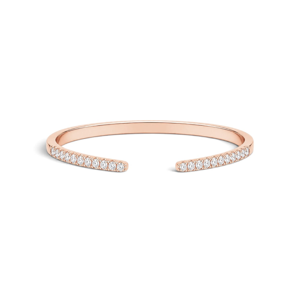 A slim open cuff bracelet in rose gold, featuring rows of small clear stones along both ends, shown on a plain white background.