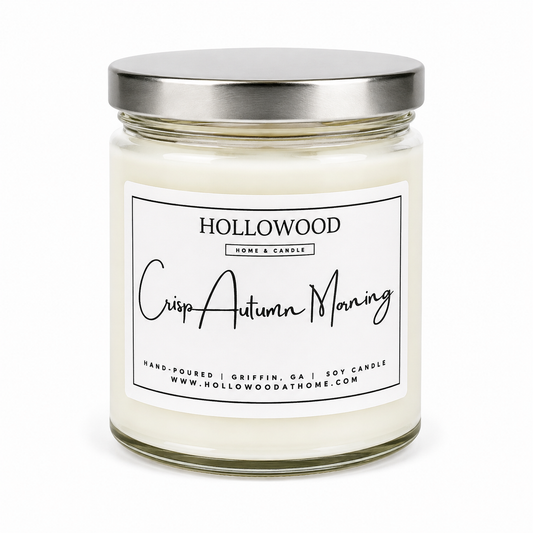 A glass jar candle with white wax and a brushed silver metal lid, featuring a white label with black text that reads 'HOLLOWOOD HOME & CANDLE' and 'Crisp Autumn Morning'.