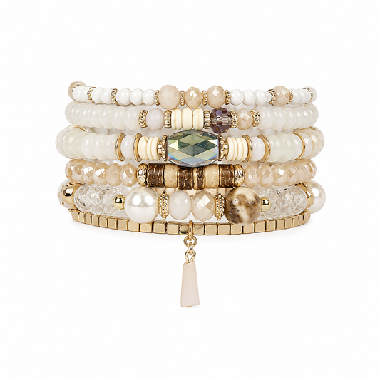 A stack of five beaded stretch bracelets with gold-tone metal accents, featuring cream, white, and beige beads, textured stone details, and a central faceted green gemstone, with a small dangling tassel charm.