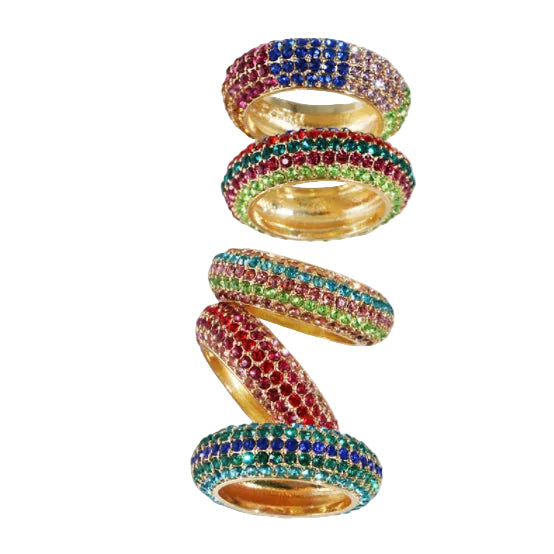 A set of four gold-plated pave rings stacked vertically in a spiral arrangement on a solid white background. Each ring is embellished with multiple rows of colorful gemstones, including blue, red, green, and pink.