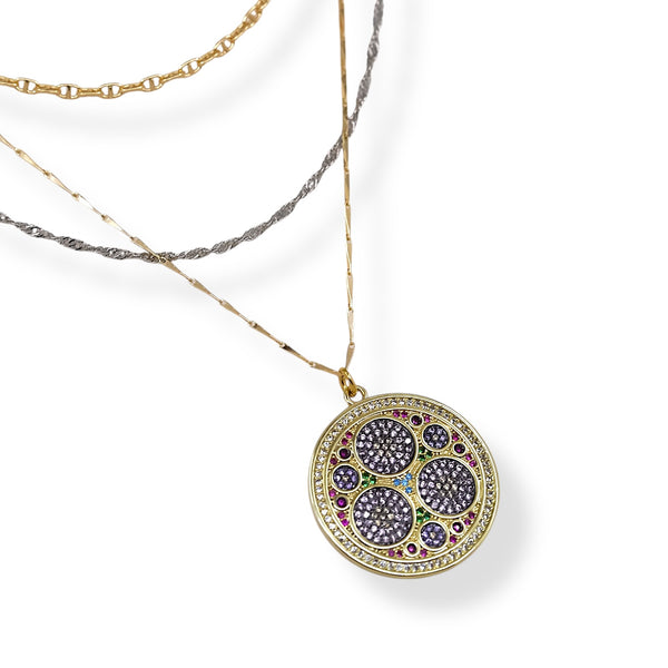 Gold necklace with a round pendant featuring colorful gemstones on a white background